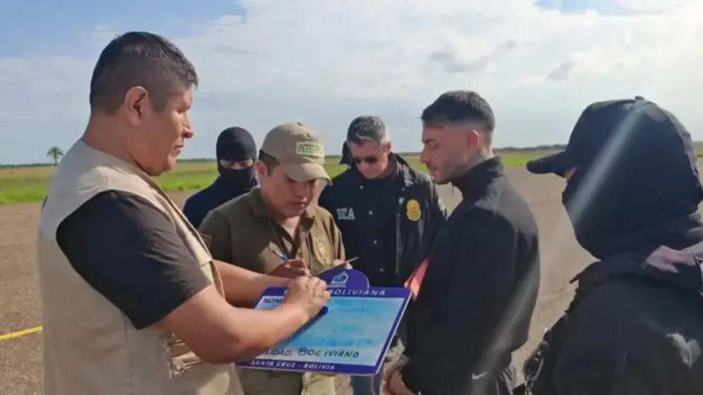 Agentes de seguridad de Bolivia y la DEA revisando documentos junto a Sebastián Marset sentado tras su captura en Santa Cruz de la Sierra.