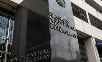 Monedas de peso uruguayo y billetes de dólar estadounidense sobre una superficie plana.