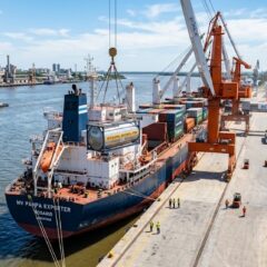 Barco de carga en un puerto agroindustrial argentino realizando la carga de granos y subproductos para exportación.