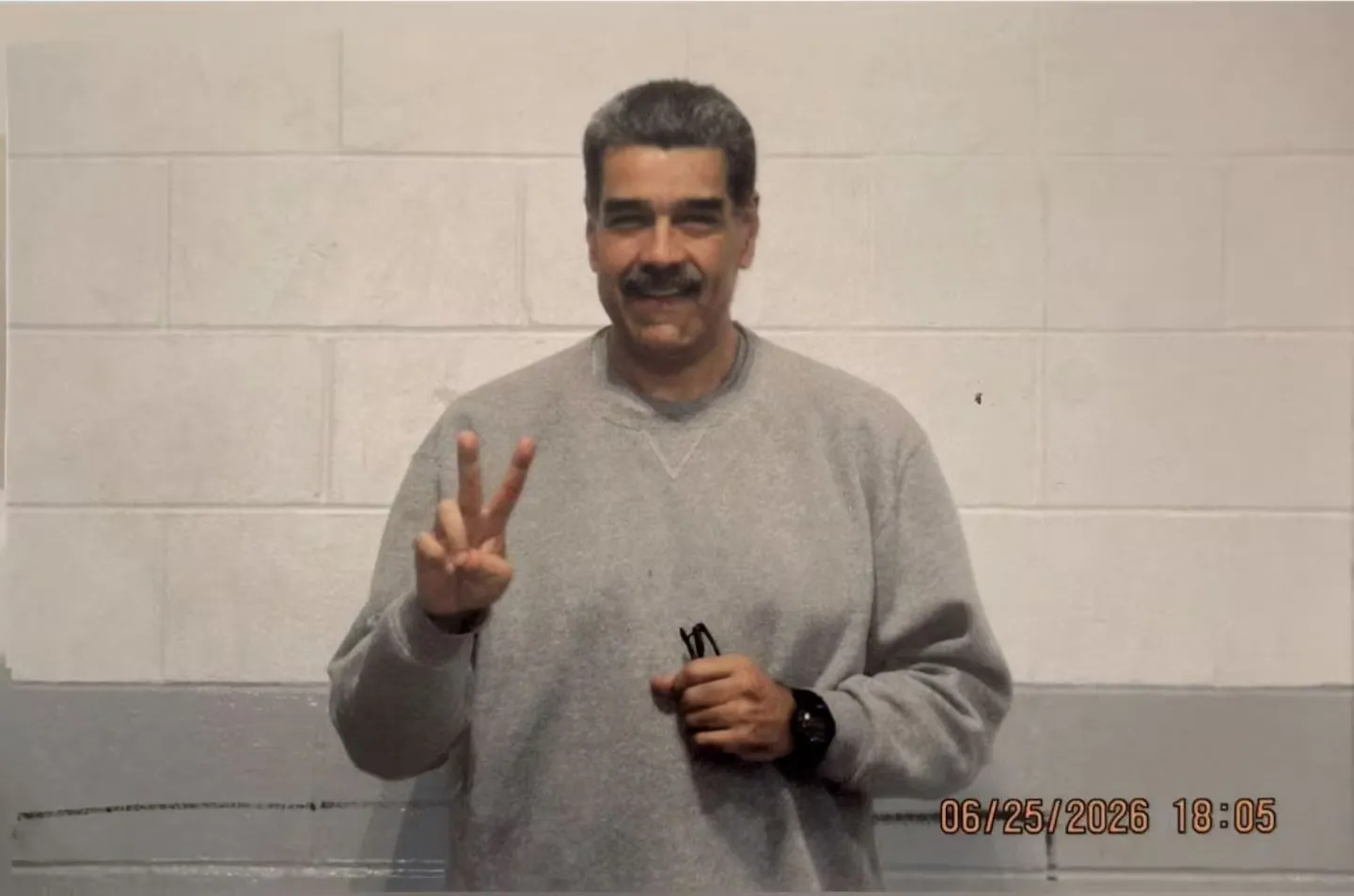 Nicolás Maduro posando en indumentaria deportiva gris con los dedos en forma de "V" en el penal de Nueva York.