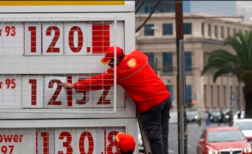 Estación de servicio en Santiago de Chile con mangueras de combustible y cartel de precios.
