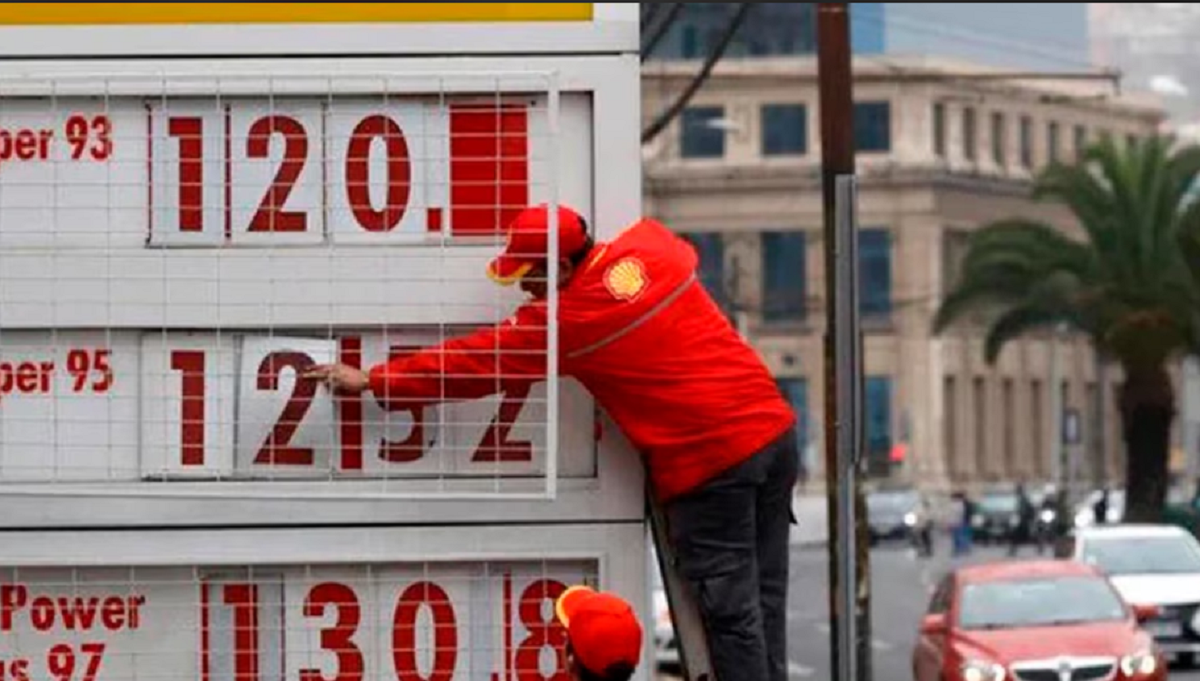 Estación de servicio en Santiago de Chile con mangueras de combustible y cartel de precios.