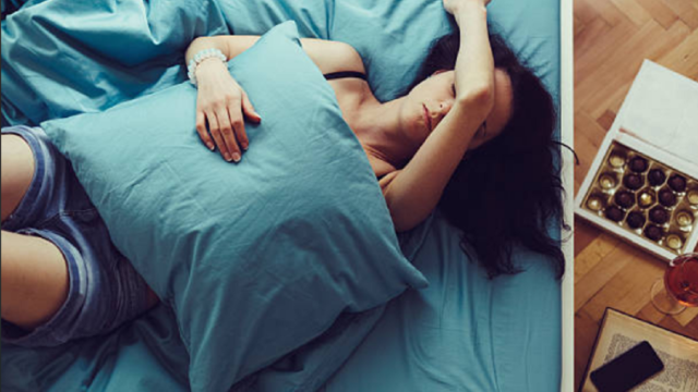 Persona descansando en la cama con gesto de molestia por dolor de cabeza.