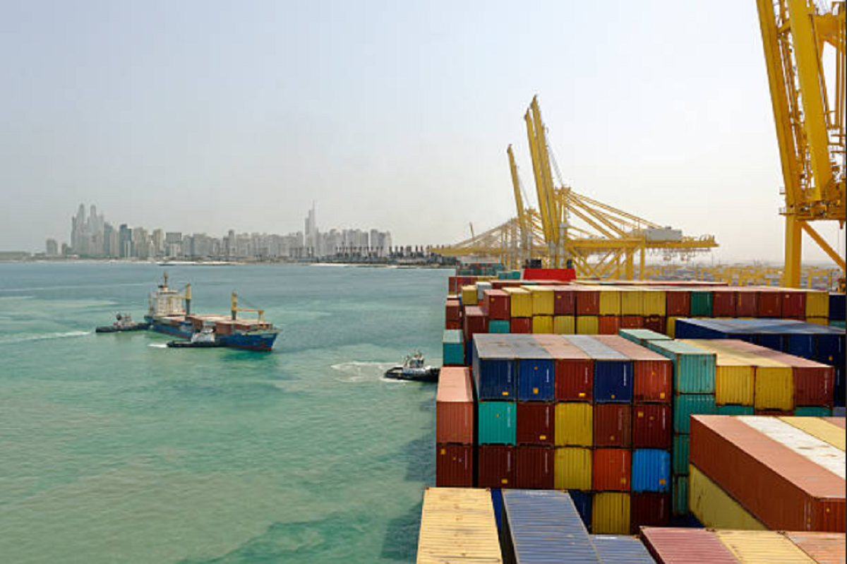 Camión transportando contenedores de carga en zona portuaria.