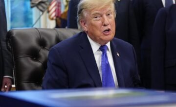 Donald Trump dando un discurso en un estrado durante un acto político.