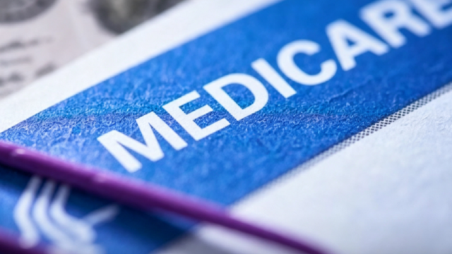 Beneficiario de la tercera edad sosteniendo la tarjeta oficial de Medicare.
