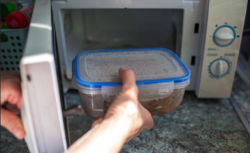 Recipiente plástico dentro de un horno microondas encendido con comida.
