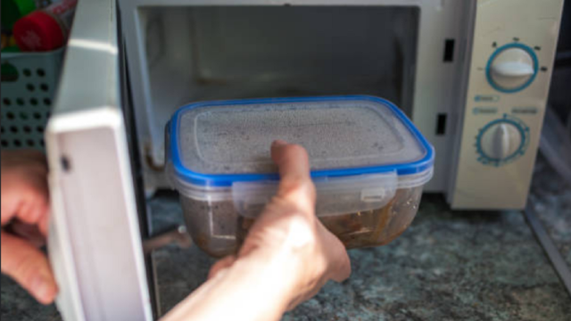 Recipiente plástico dentro de un horno microondas encendido con comida.