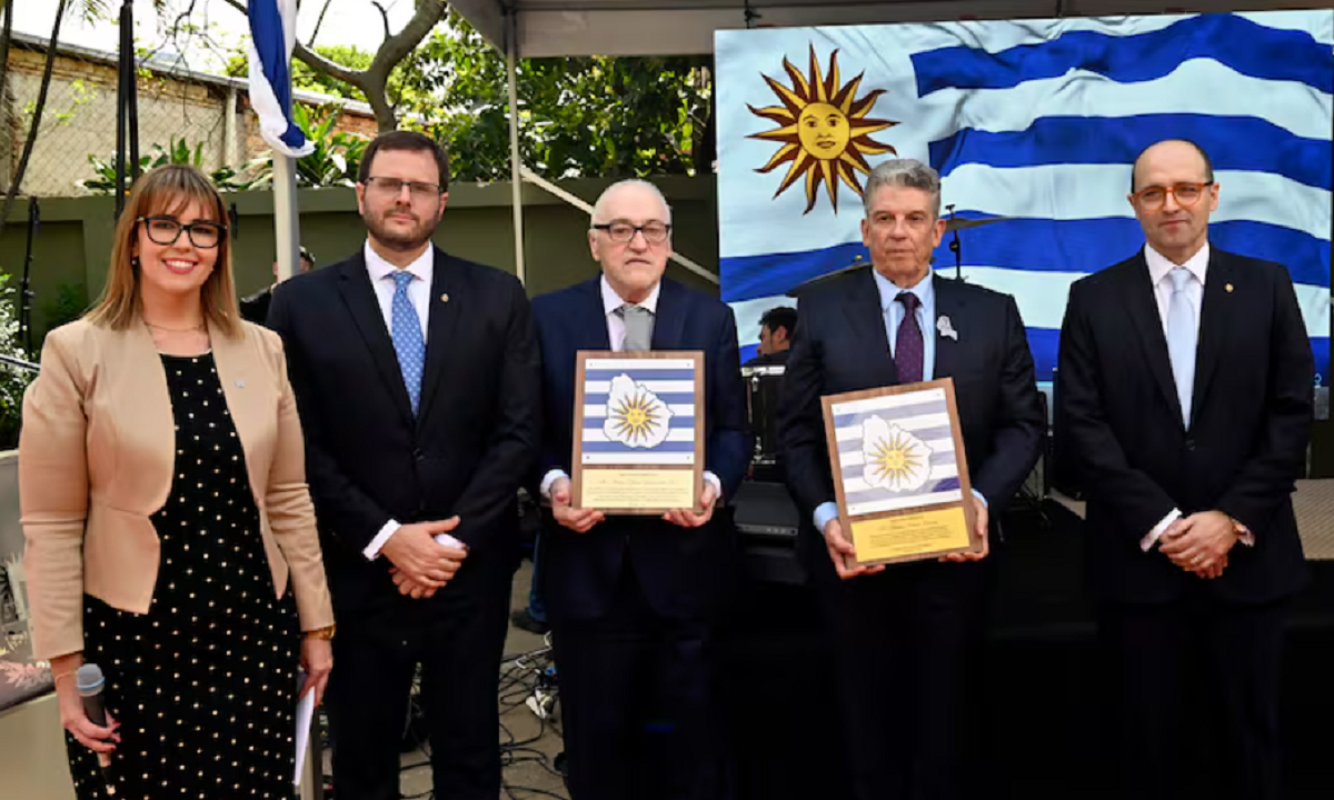 Autoridades y homenajeados posan con la bandera de Uruguay durante la recepción.