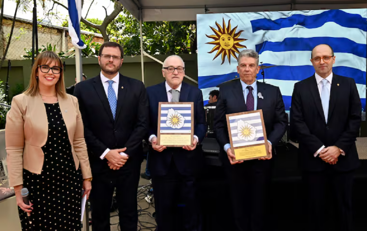 Autoridades y homenajeados posan con la bandera de Uruguay durante la recepción.