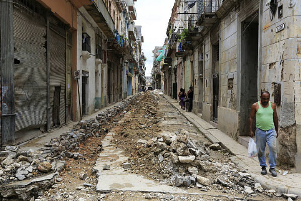 Persona mayor caminando frente a fachadas deterioradas en una calle de La Habana.