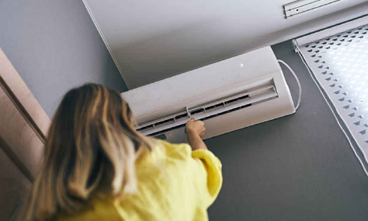 Control remoto y equipo de aire acondicionado encendido en una vivienda durante el verano.