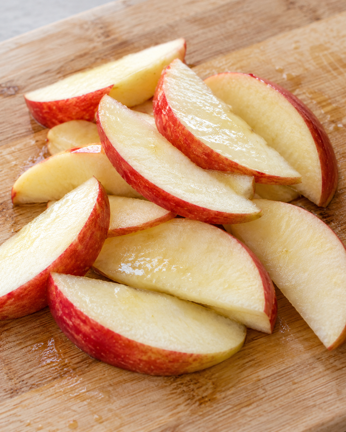 Rodajas de manzana fresca tratadas con jugo de limón sobre una tabla de cortar.