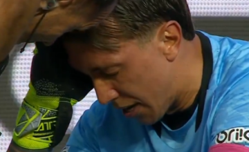 Fernando Muslera sentado en el césped de su área recibiendo atención médica.