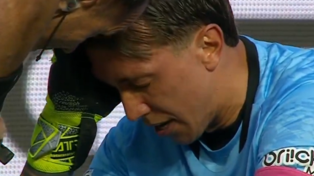 Fernando Muslera sentado en el césped de su área recibiendo atención médica.