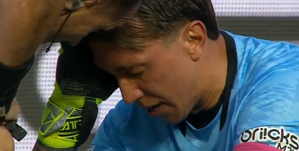 Fernando Muslera sentado en el césped de su área recibiendo atención médica.