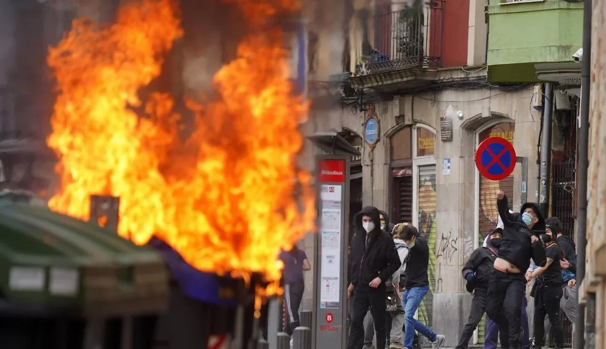 Efectivos de la Ertzaintza desplegados en la Avenida Lehendakari Agirre frente a barricadas en llamas.