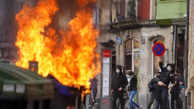 Efectivos de la Ertzaintza desplegados en la Avenida Lehendakari Agirre frente a barricadas en llamas.