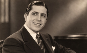 Foto histórica de Carlos Gardel sonriendo con su característico sombrero.