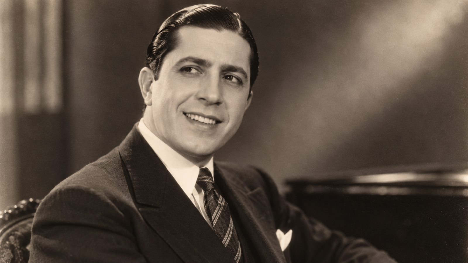 Foto histórica de Carlos Gardel sonriendo con su característico sombrero.