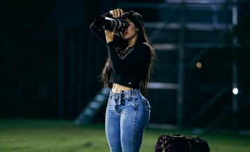 Reportera gráfica trabajando en el campo de juego durante un partido de fútbol.