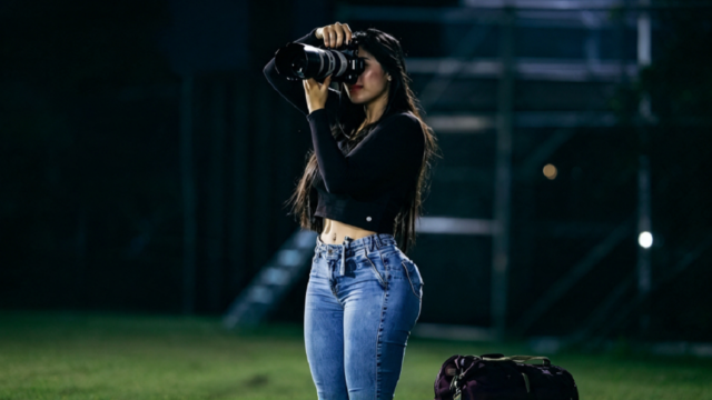 Reportera gráfica trabajando en el campo de juego durante un partido de fútbol.
