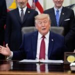 Donald Trump hablando frente a micrófonos en un acto oficial.