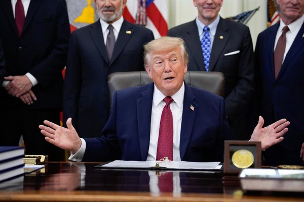 Donald Trump hablando frente a micrófonos en un acto oficial.