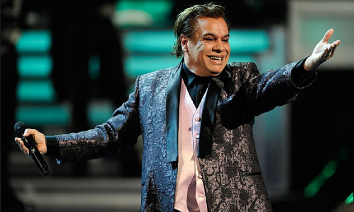 Juan Gabriel sonriendo en el escenario con traje morado.
