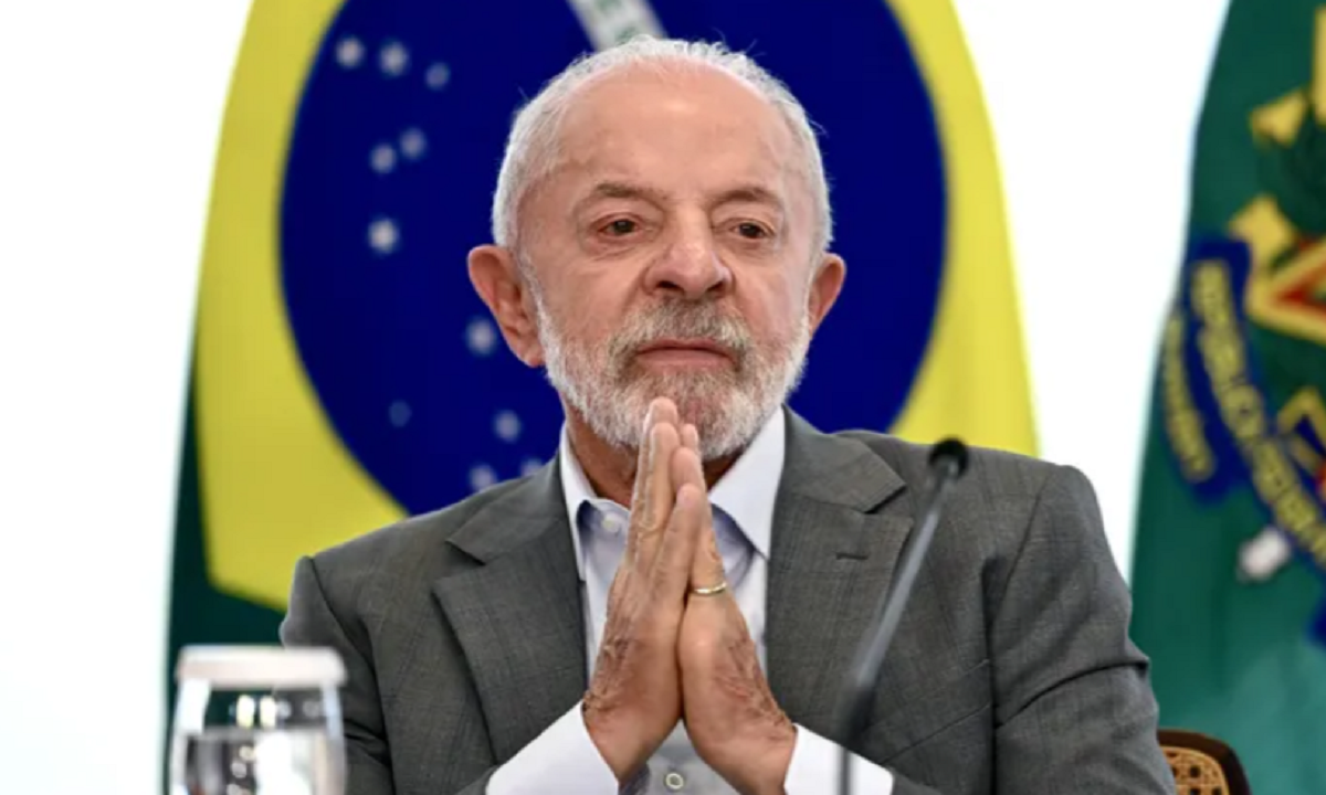El presidente de Brasil, Luiz Inácio Lula da Silva, con las manos juntas frente a la bandera de su país.