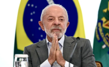 El presidente de Brasil, Luiz Inácio Lula da Silva, con las manos juntas frente a la bandera de su país.