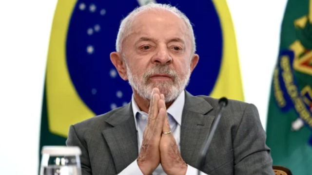 El presidente de Brasil, Luiz Inácio Lula da Silva, con las manos juntas frente a la bandera de su país.