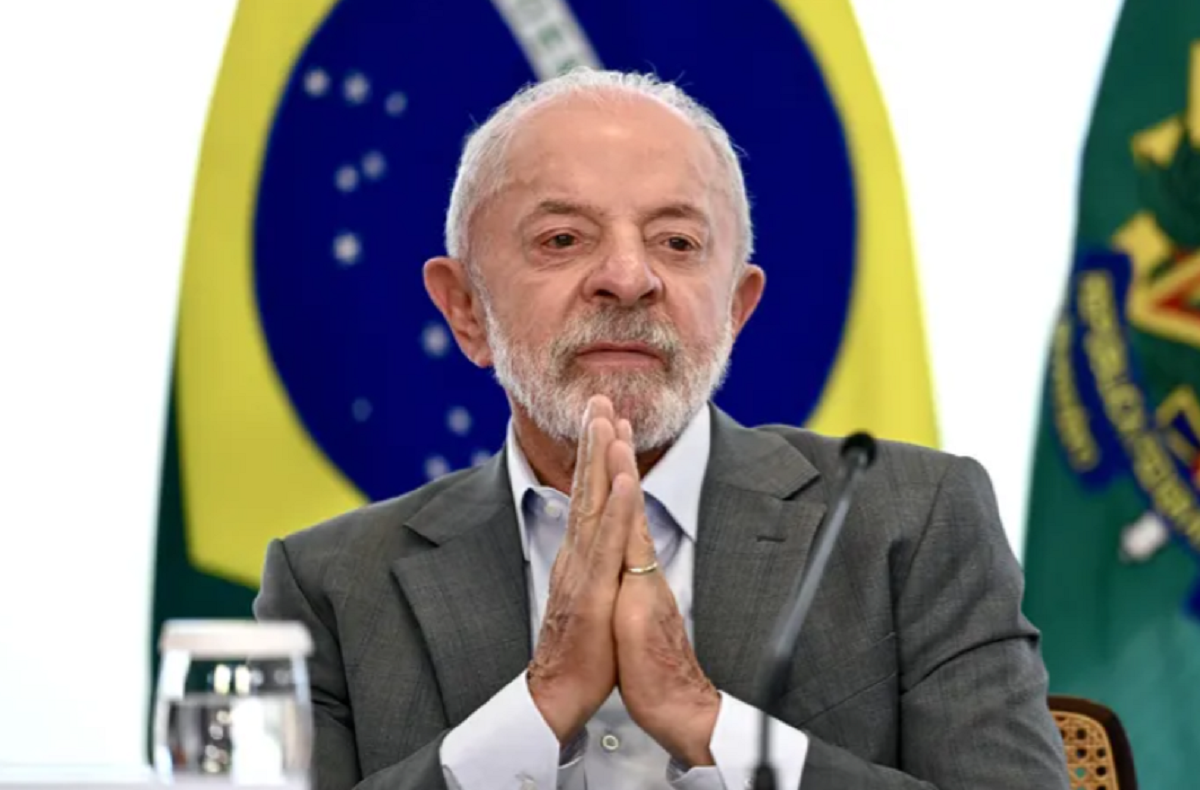 El presidente de Brasil, Luiz Inácio Lula da Silva, con las manos juntas frente a la bandera de su país.