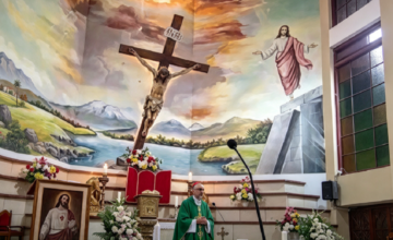 Vista del altar de una iglesia católica con una cruz de madera de gran tamaño.