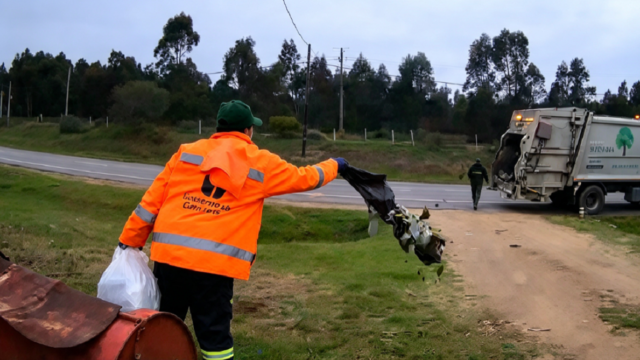 Captura de video de cámara de seguridad mostrando a un recolector arrojando basura en una casa.