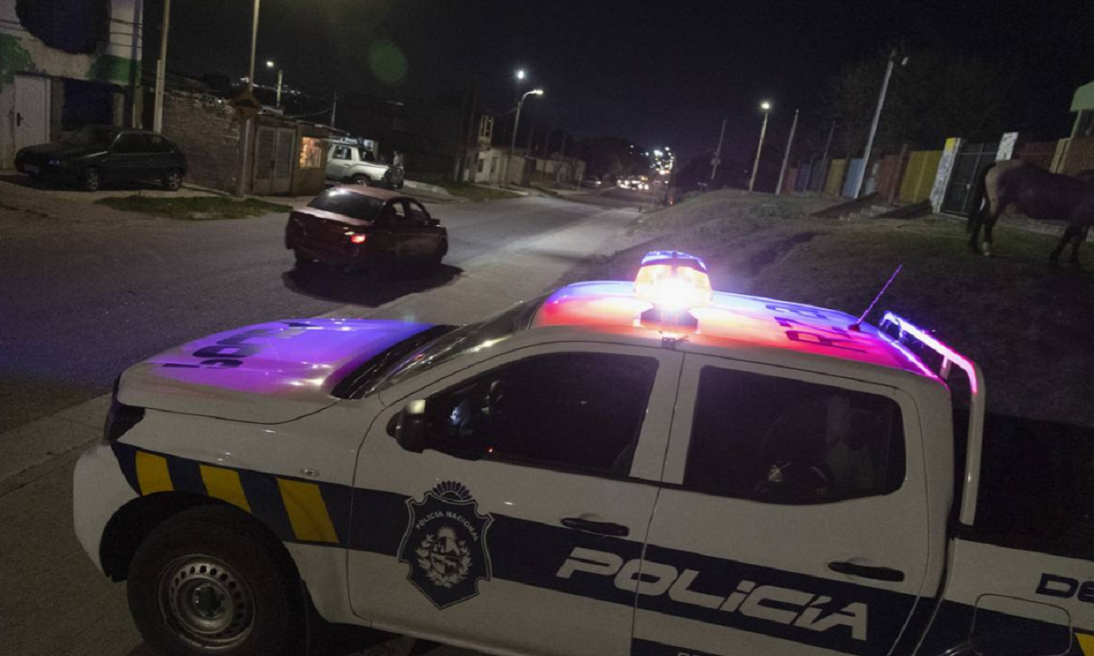 Móvil policial estacionado de noche con luces de emergencia encendidas.