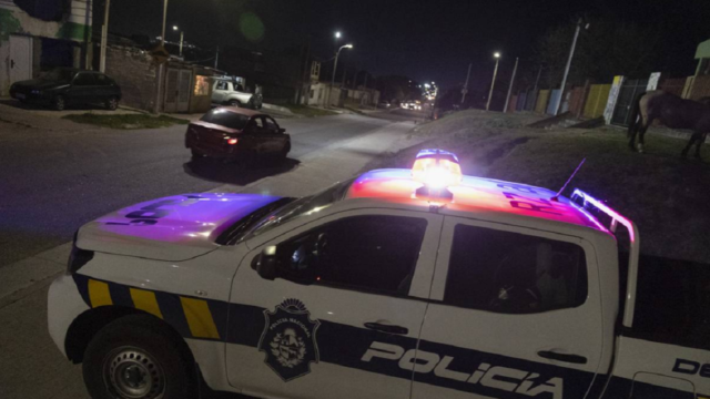 Móvil policial estacionado de noche con luces de emergencia encendidas.