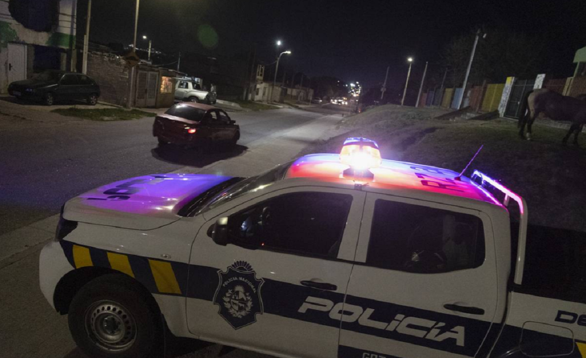 Móvil policial estacionado de noche con luces de emergencia encendidas.